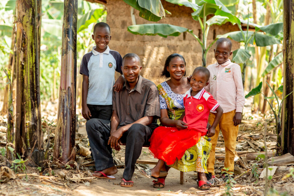 Florance and Fitimukiza and their three young children sit together in their garden.