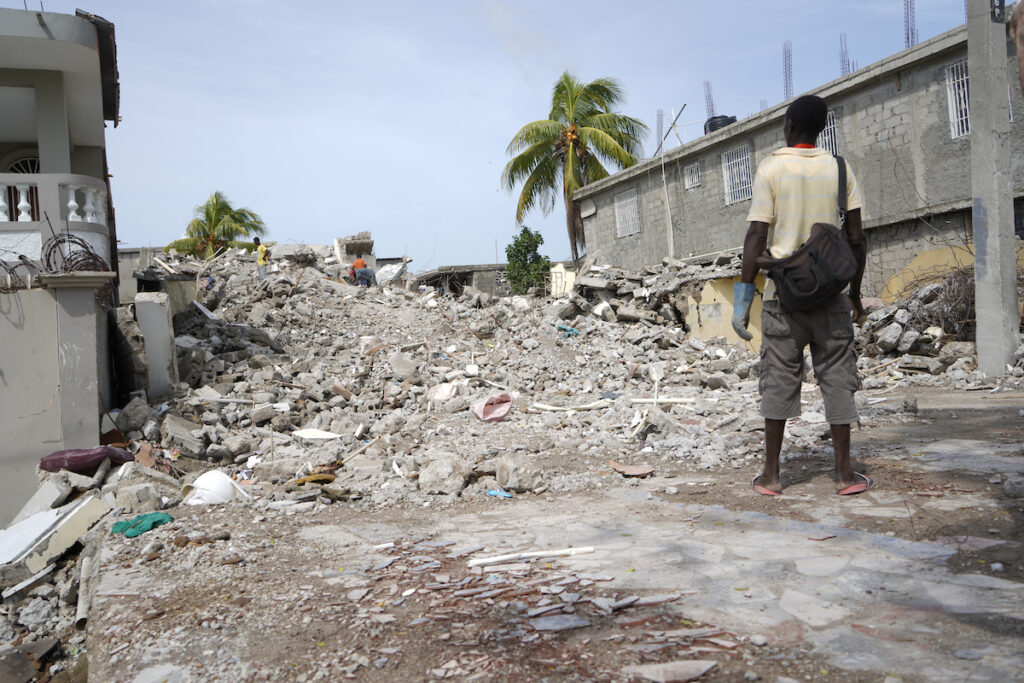 Man stares at rubble of a building caused by 2021 Haiti earthquake