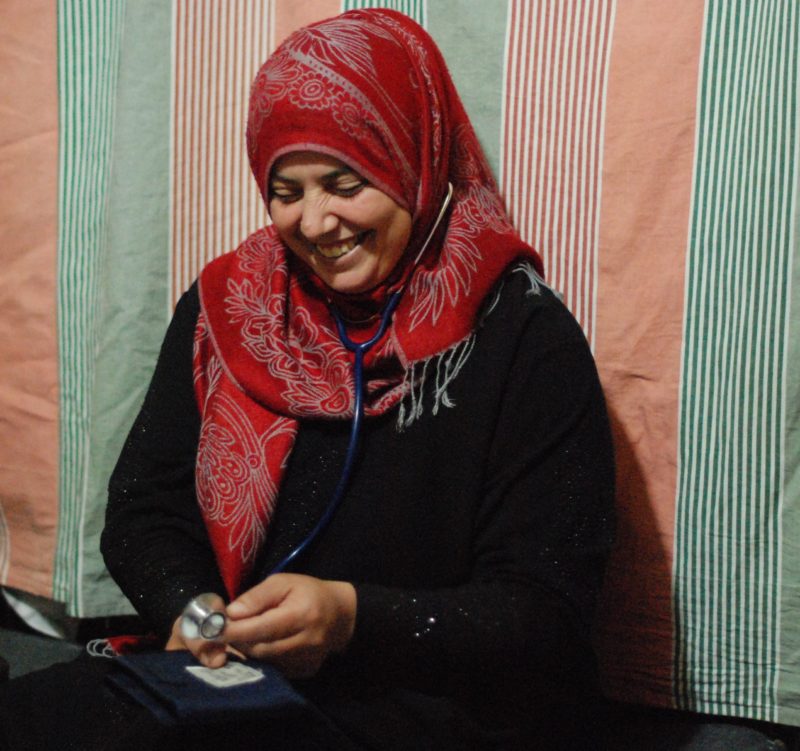 Hind, a refugee outreach volunteer in Lebanon, smiling holding a stethoscope