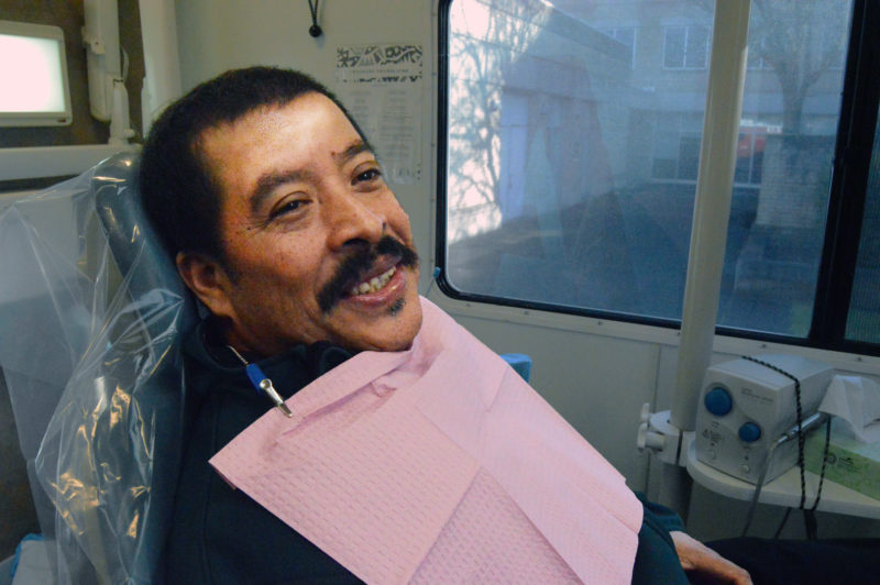 Jose, a visitor at a Mobile Dental Clinic, sitting in a chair to get one of his teeth extracted