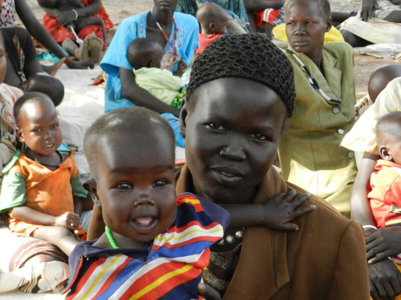 A mother posing with her smiling baby in one of the Uganda refugee camps