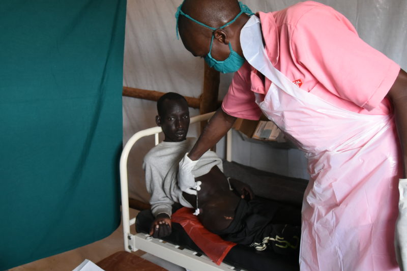 A South Sudanese man, being treated for her gun shot wound by a Medical Teams staff member