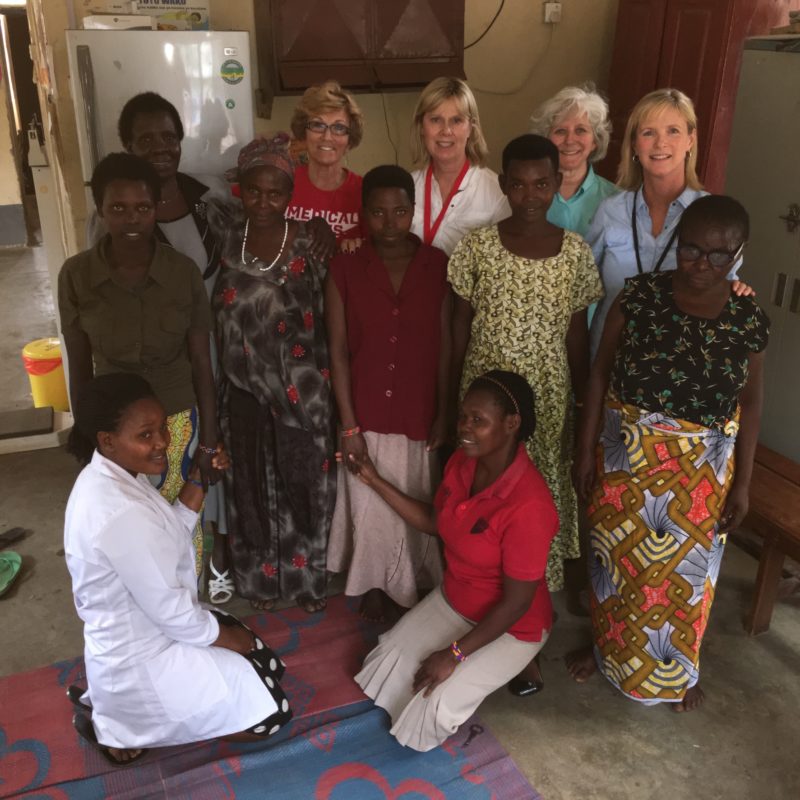 Four medical teams international volunteers, standing and smiling with women in Uganda who suffer from obstetric fistulas
