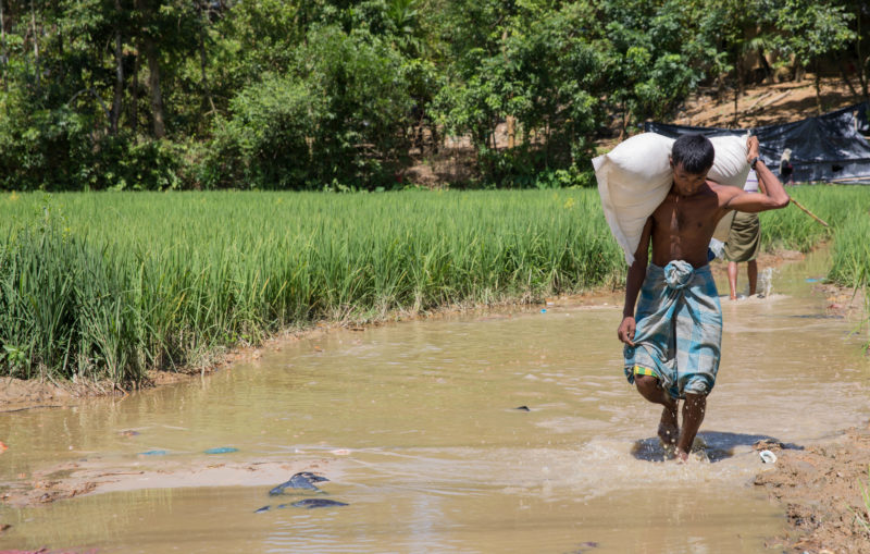 A Rohingya man walking through a muddy river within the settlement in Bangladesh, a breeding ground for diseases