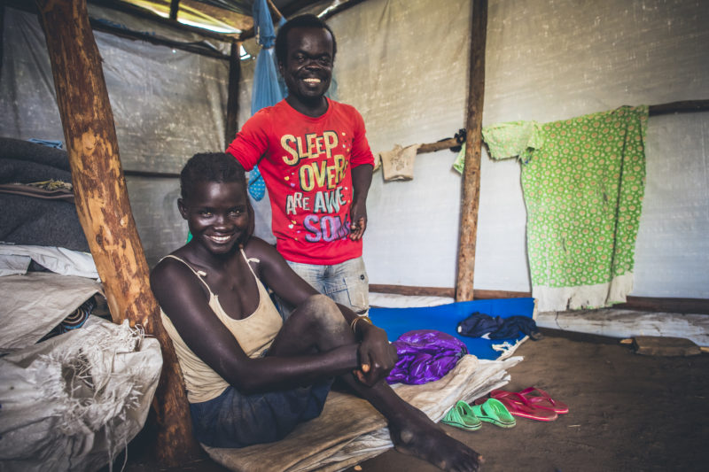Rose and her husband, smiling widely in their refugee camp tent