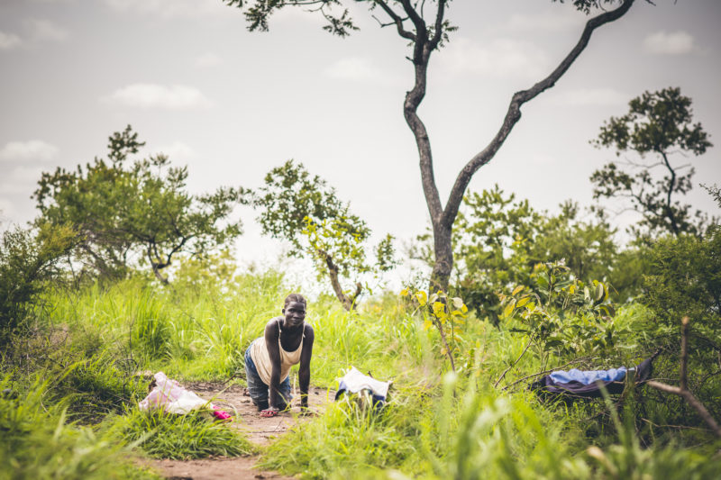 Rose, a Ugandan refugee from South Sudan, crawling on the dirt ground due to her disabled legs