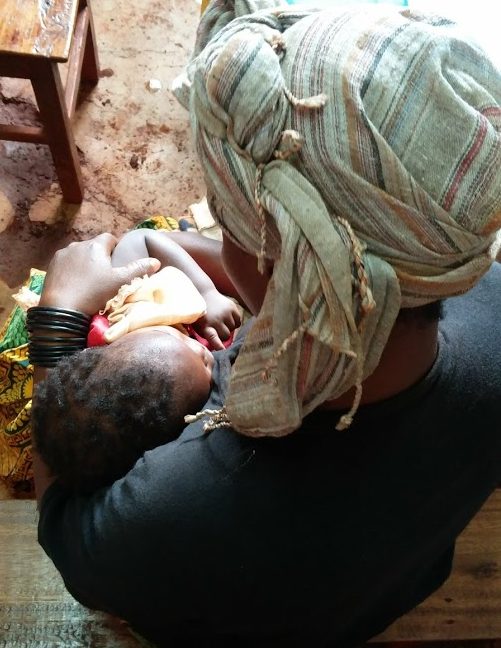 A Tanzanian mother holding her sleeping baby after receiving medical care