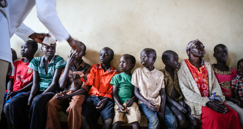 Uganda refugee children receiving medical care, including screening, vaccinations, malaria treatment, and more