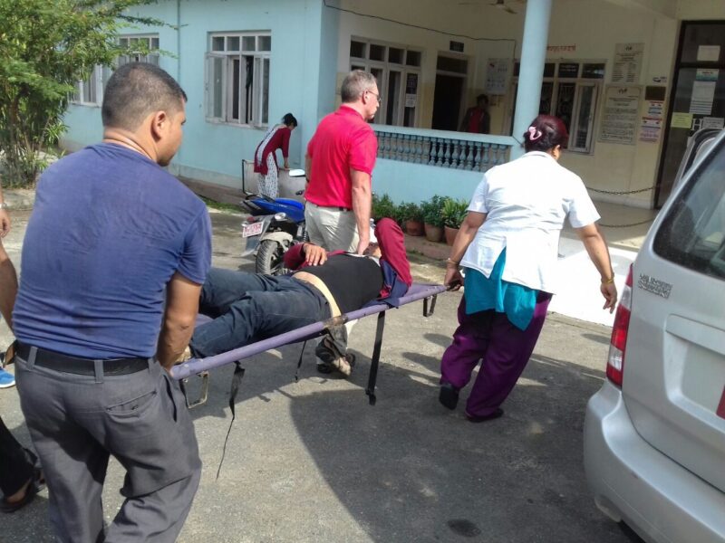 A Nepalese man being carried on a stretcher to the hospital after being hit off his motorcycle