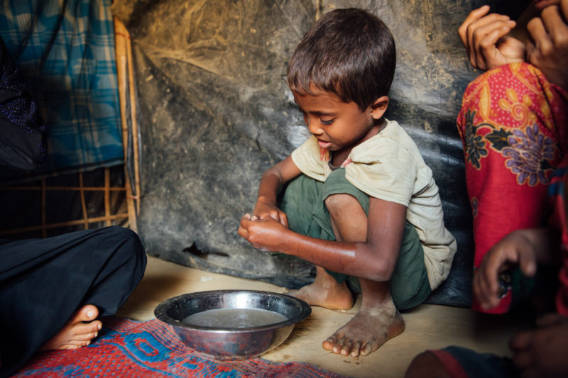 A young Rohingya boy learning how to wash his hands from a refugee community health volunteer