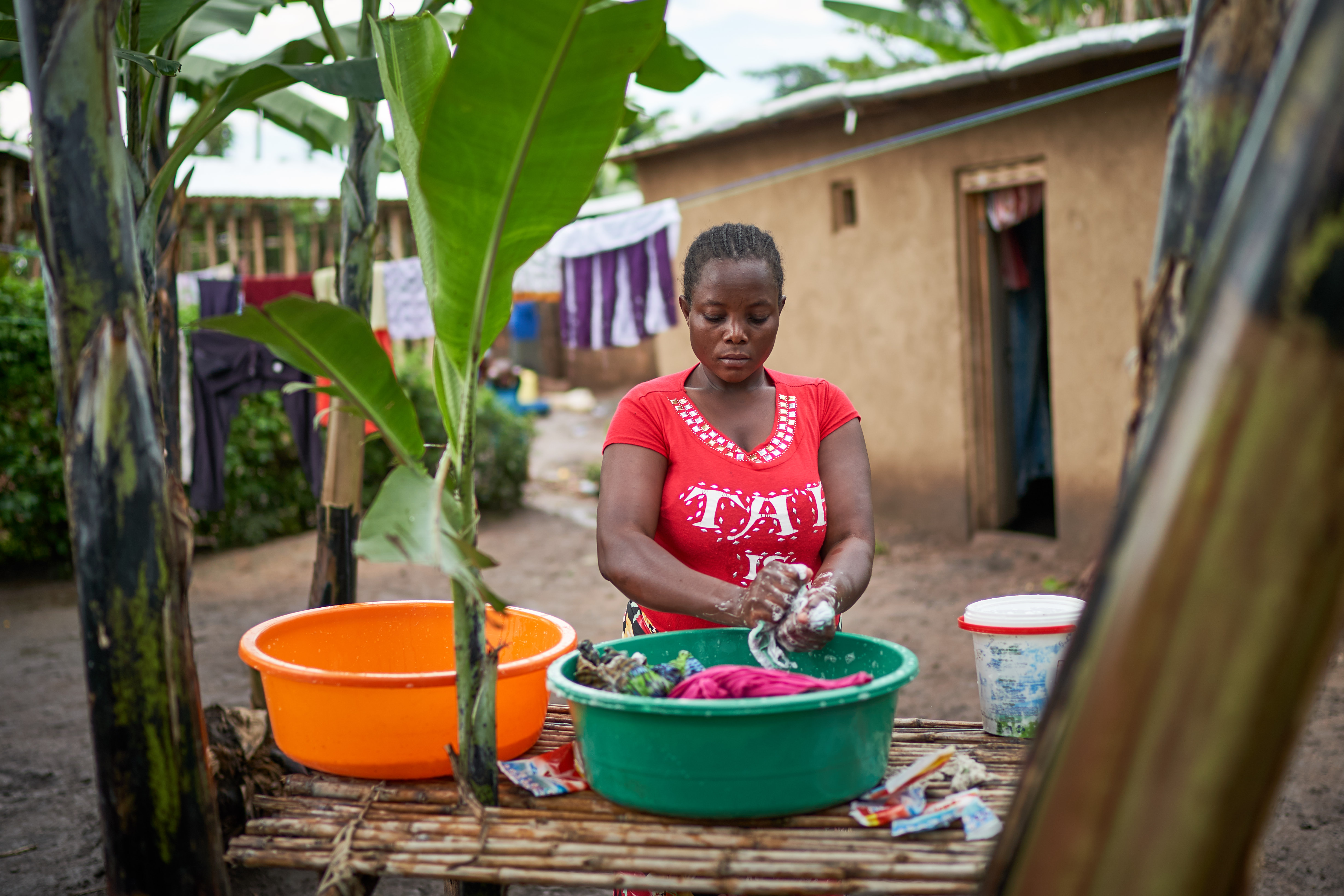 Janet washes clothes outside her home in Kyangwali refugee settlement in Uganda