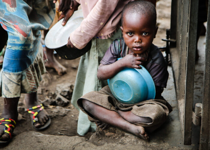 A refugee child waits for food at a migration transit center as part of the DRC Response program.