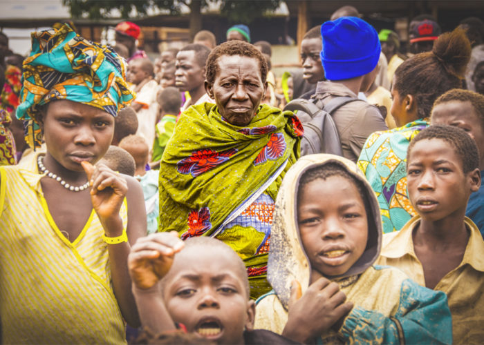 An older woman stands in a crowd with other refugees in Uganda, 2018.