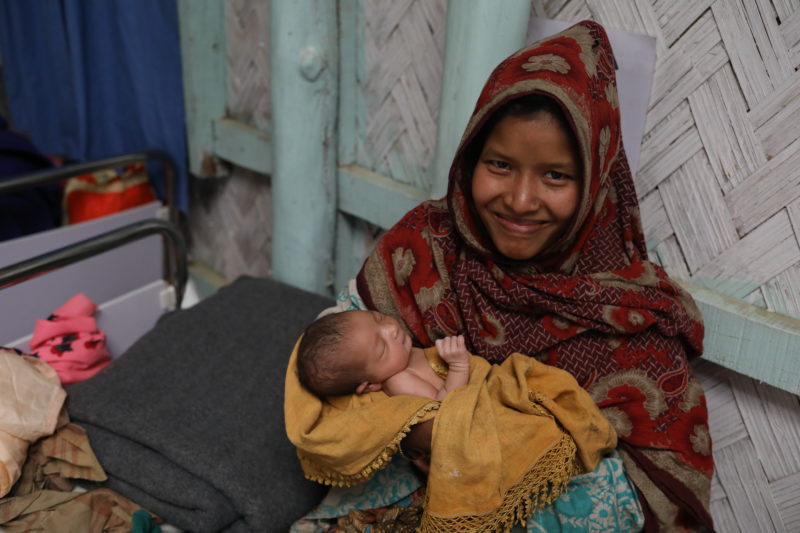 Nur Ankiz smiling and holding her newborn baby in a Medical Teams International clinic
