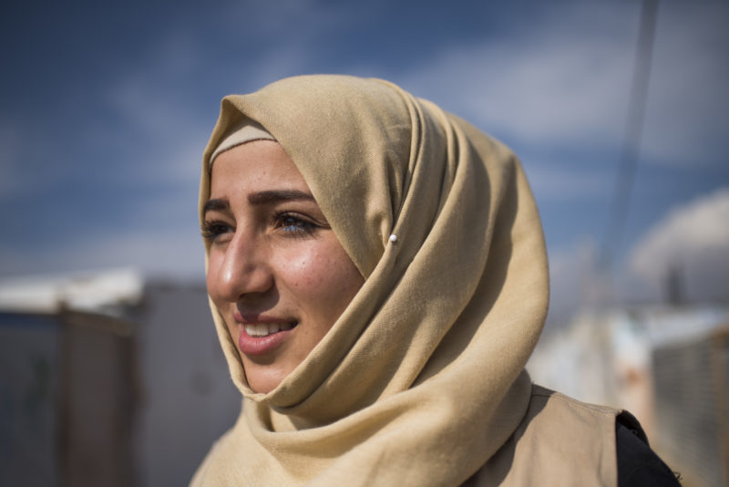 Shaza, smiling and hopeful, surrounded by the refugee camp she calls home