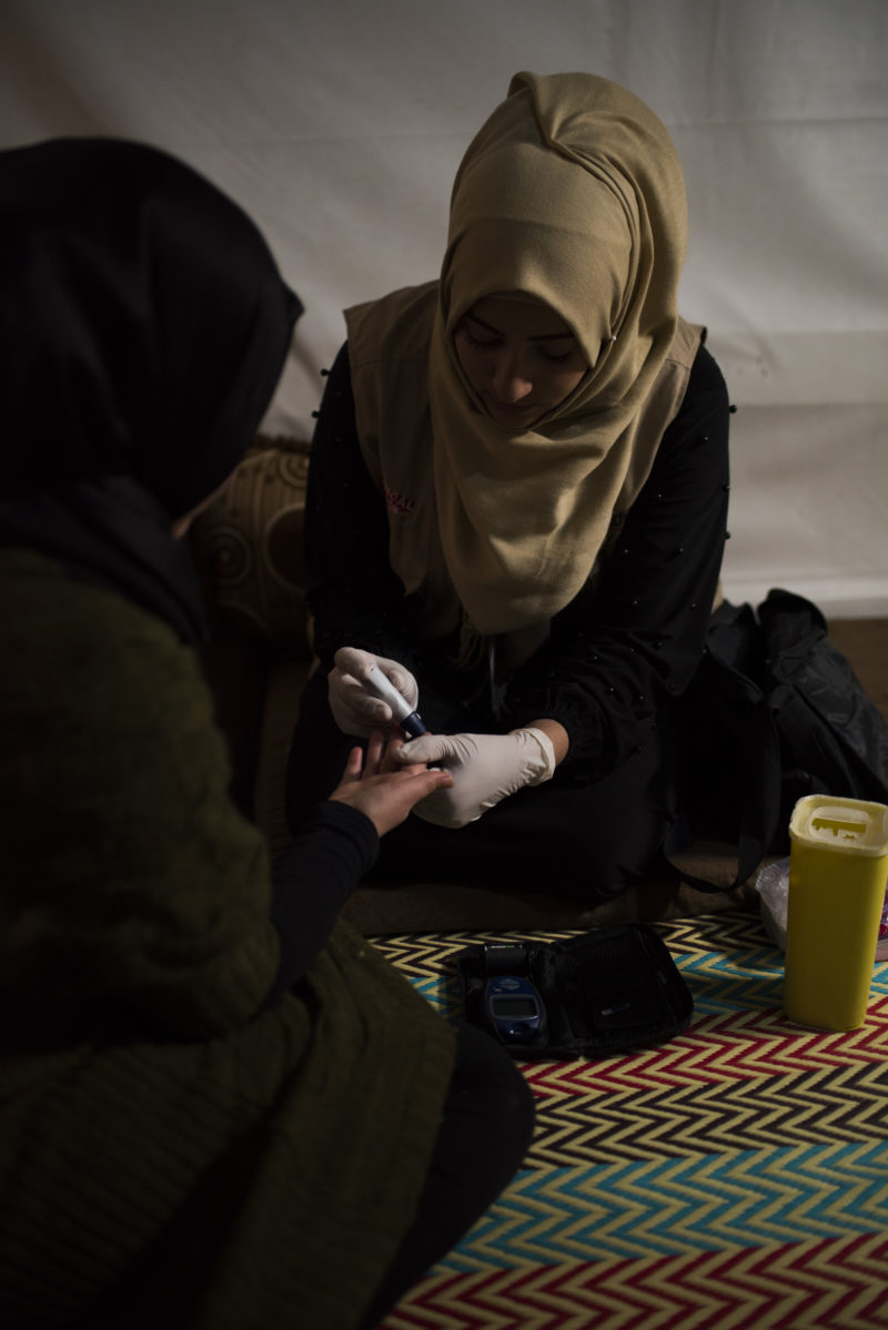 Shaza, the Senior Refugee Outreach Volunteer, giving medical care to a child with diabetes in a Lebanon refugee camp