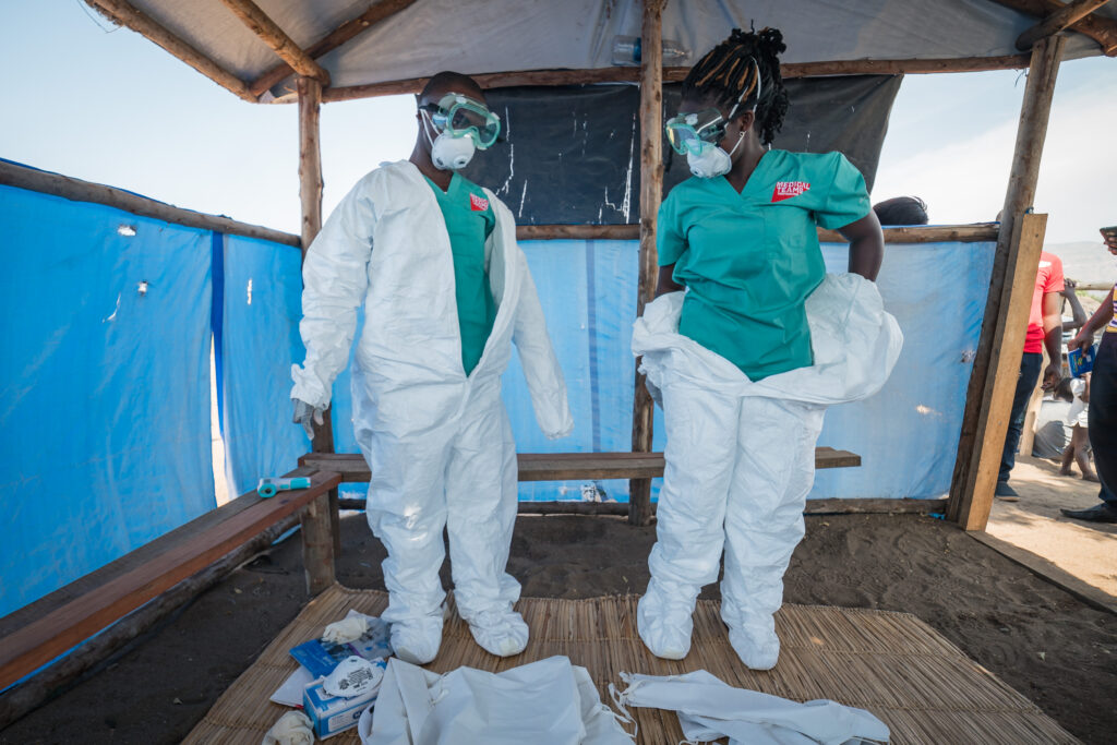 A man and woman putting on protective clothing to screen for Ebola
