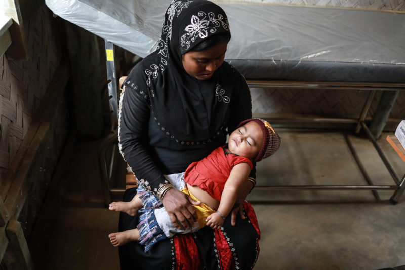 Jomila, a Rohingya refugee woman, holding her baby who suffered with pneumonia due to the monsoon season in Bangladesh