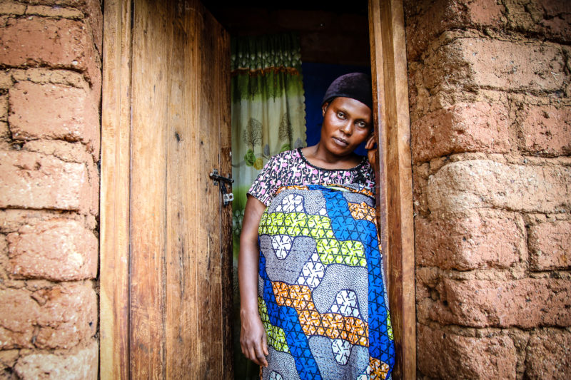 Suzanne, a refugee in the Nyarugusu camp, standing in the doorway of her home in Tanzania