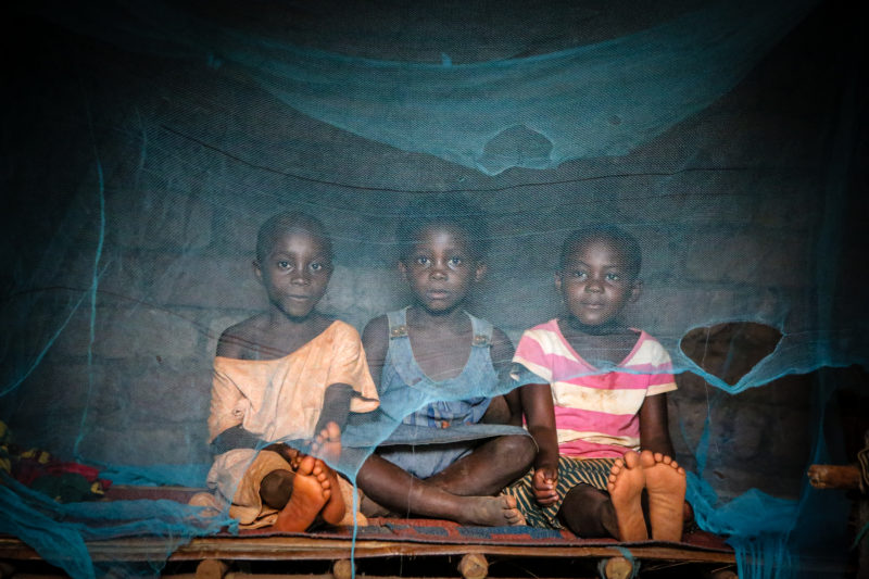 Three of Suzanne’s children, sitting underneath their damaged mosquito nets that are suppose to protect them from malaria