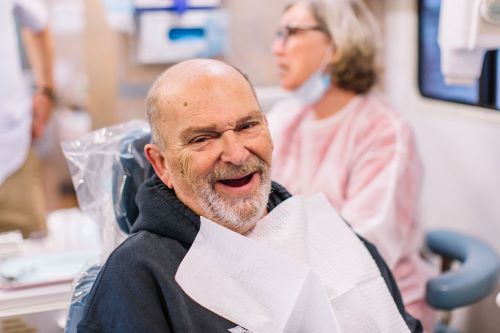 Tim, a visitor at a Mobile Dental Clinic, sitting in a chair smiling with a teeth less grin