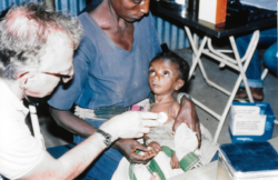 Historical photo, Ethiopian child and Dr. Cravens listening to his heartbeat 