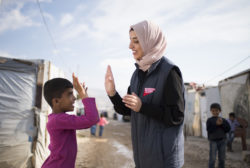 Shaza, a community health worker in Lebanon, high-fives a Syrian refugee girl