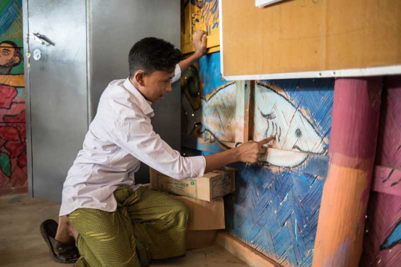 Abdoushukur, one of the Rohingya refugee boys, showing his art from art therapy