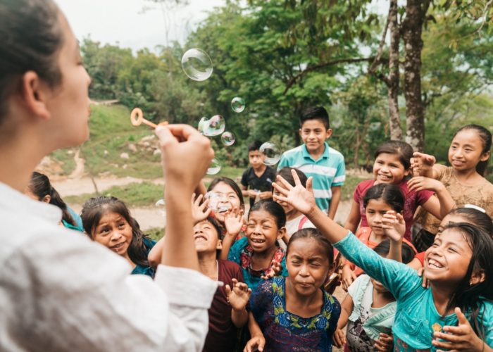 Guatemala community health worker blowing bubbles to children, 2019.