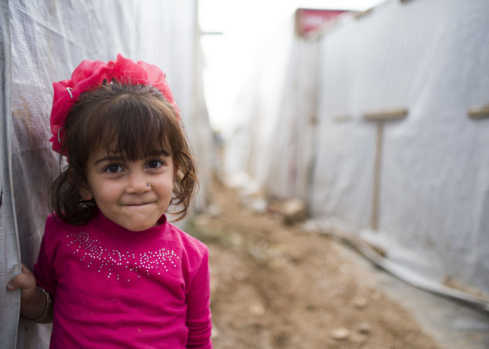 A Lebanon girl smiling outside in her refugee settlement