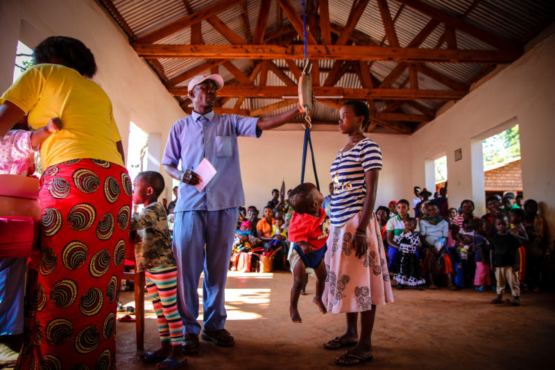 A community health worker using the growth monitoring for a young children