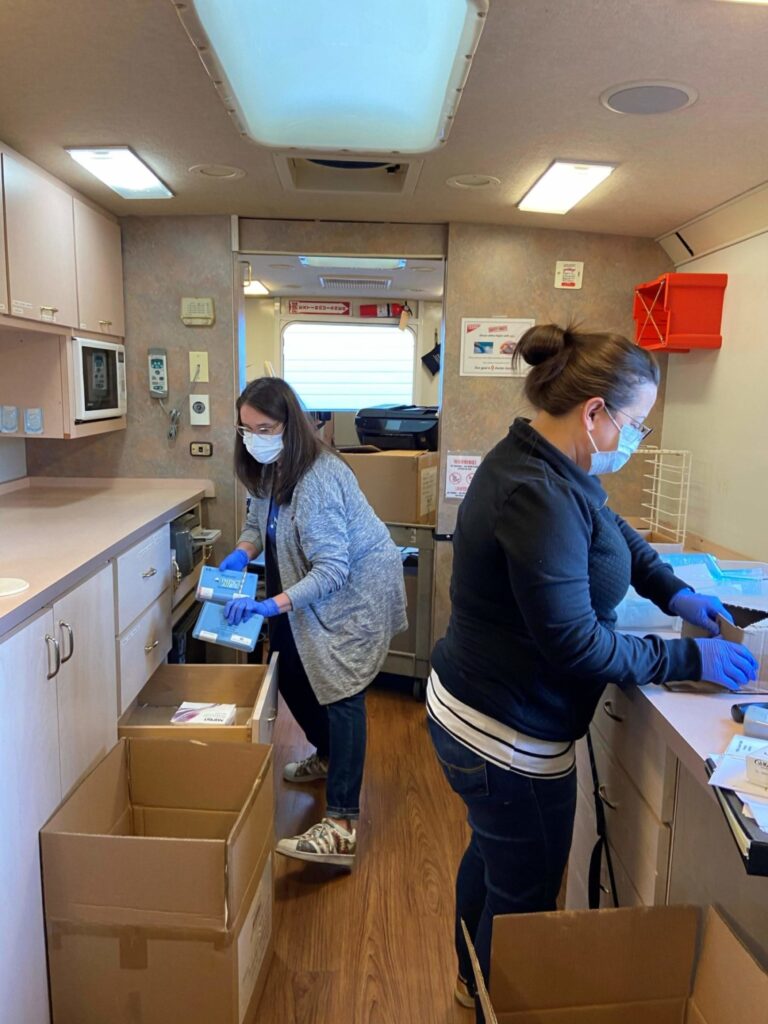 Two Medical Teams staff organizing personal protective gear on a Dental Van