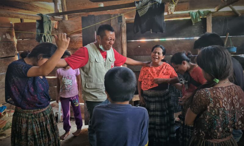 Staff member Romeo Lem prays for Luisa after she lost her husband and home in a landslide caused by Hurricanes Eta and Iota.