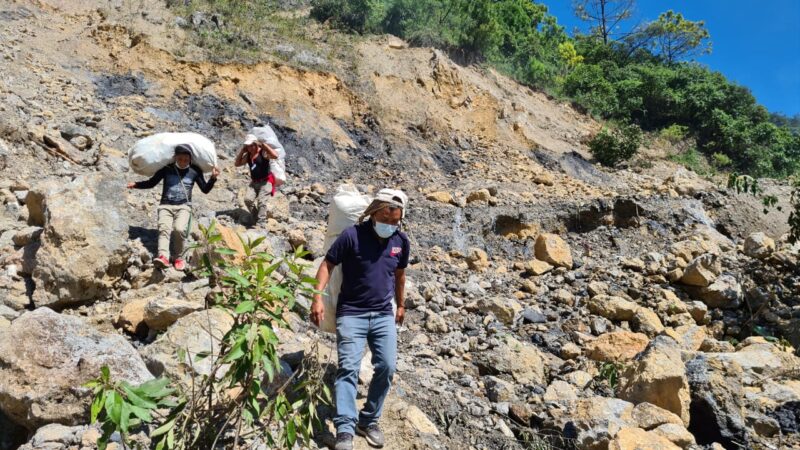 Staff members Celestino, Romeo and Carlos carry hygiene kits on foot to villages where the route was blocked by landslides.