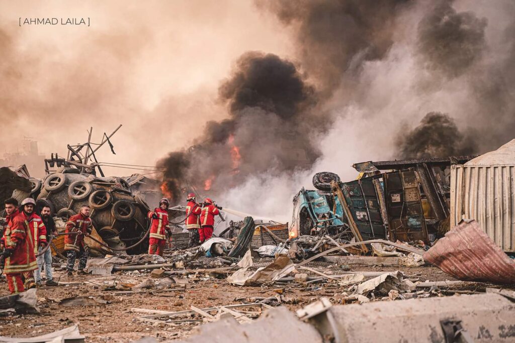 firefighters hose down flames amidst rubble