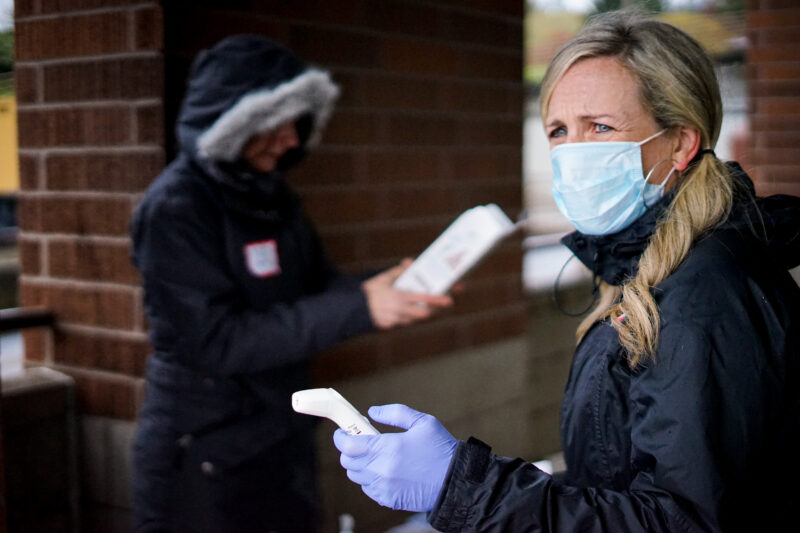 Volunteer Satine holds an infrared thermometer at an emergency dental clinic. 