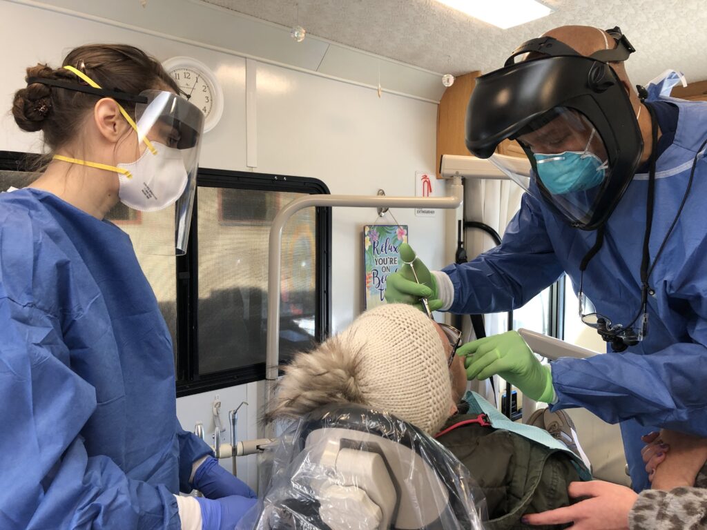 Gloriana is cared for by a dentist and dental assistant at a Mobile Dental Clinic