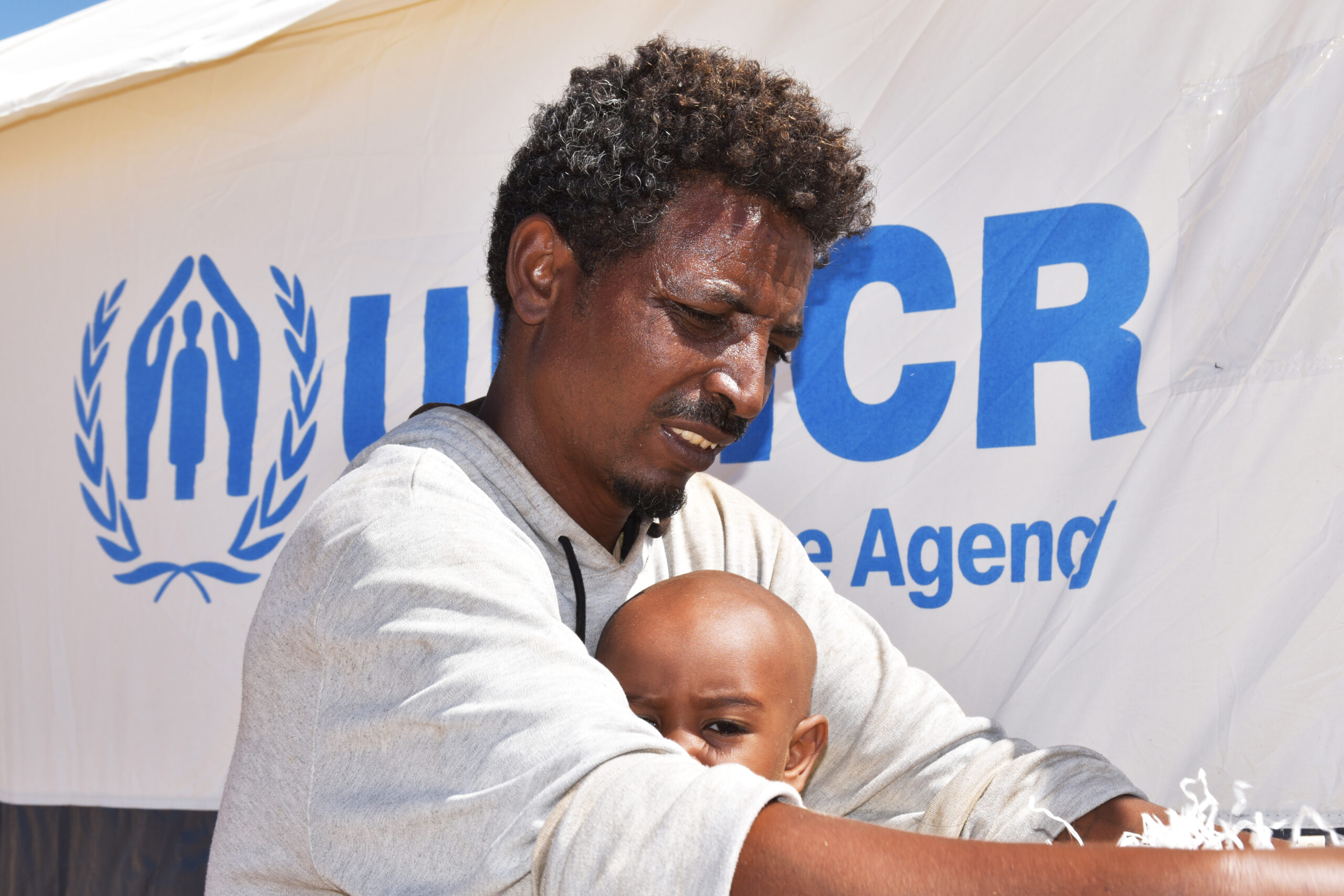 An Ethiopian man holding his son sitting outside 