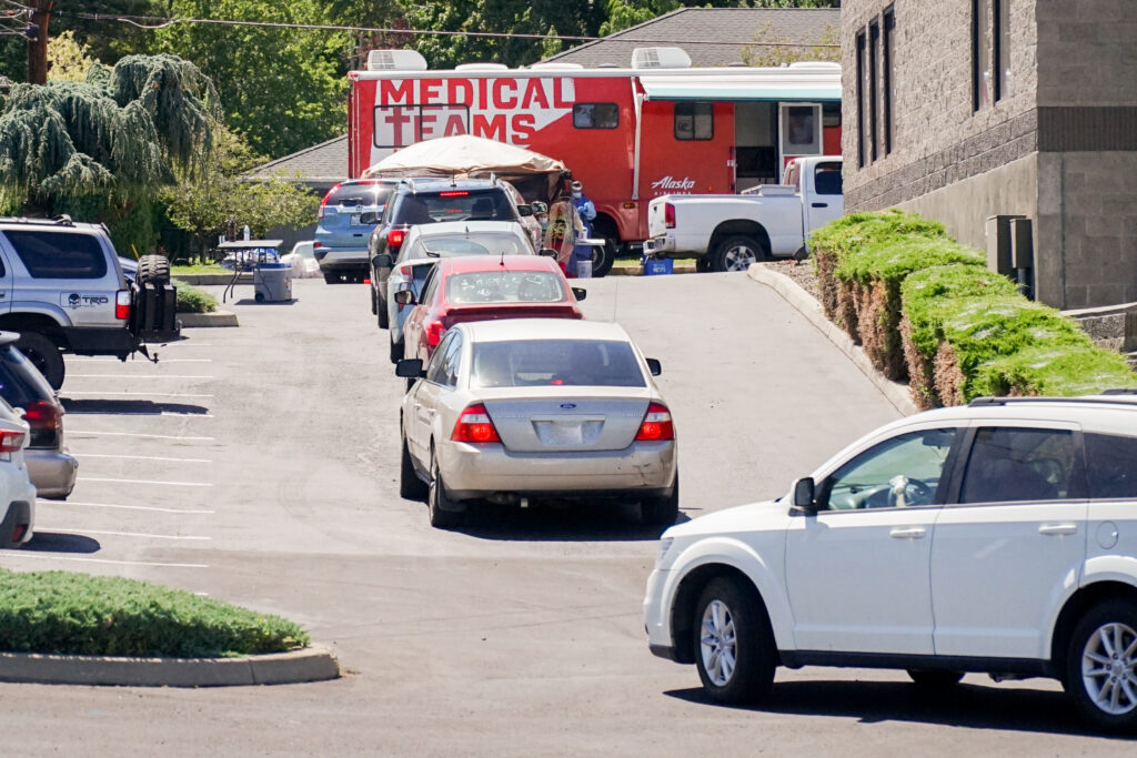A line of cars wait in front of a Medical Teams mobile testing center