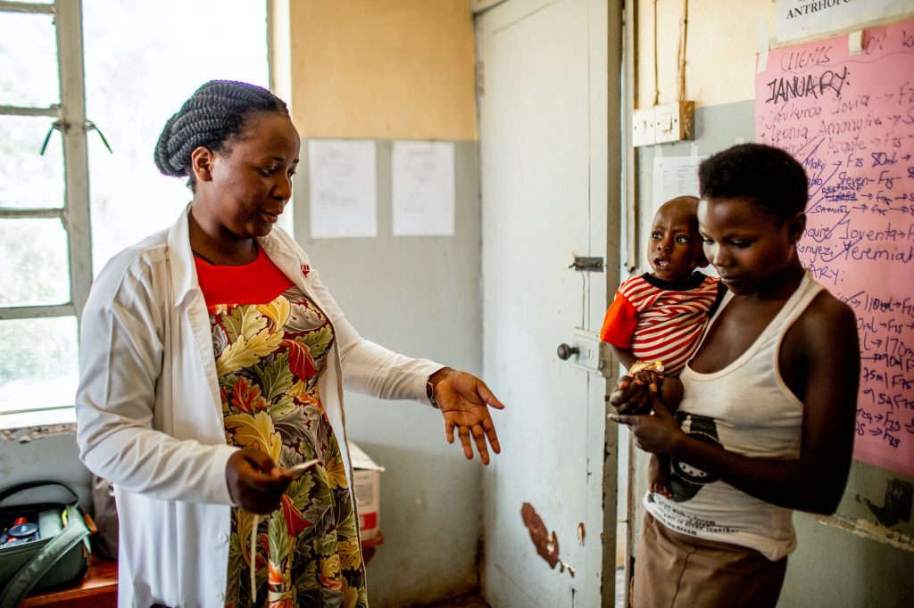 Monicah talking to a mother and child about nutrition.