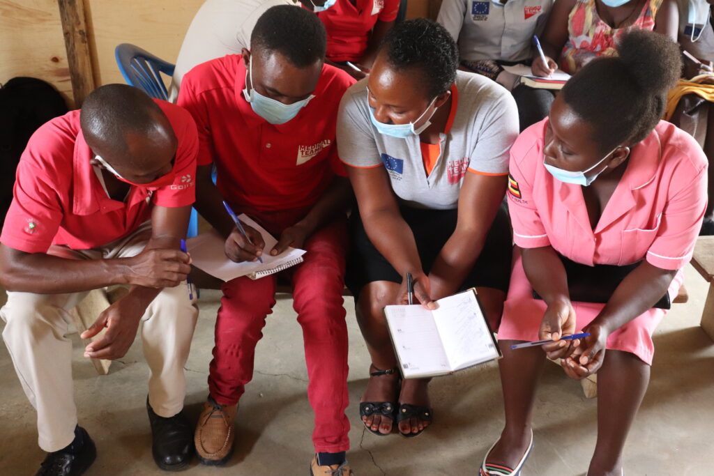 Four staff members compare notes at a training in Uganda