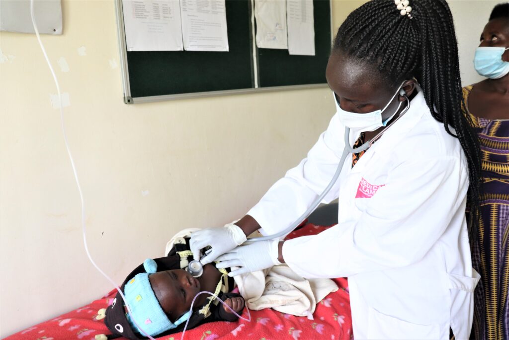 A clinical officer treating a baby for malaria with an IV.