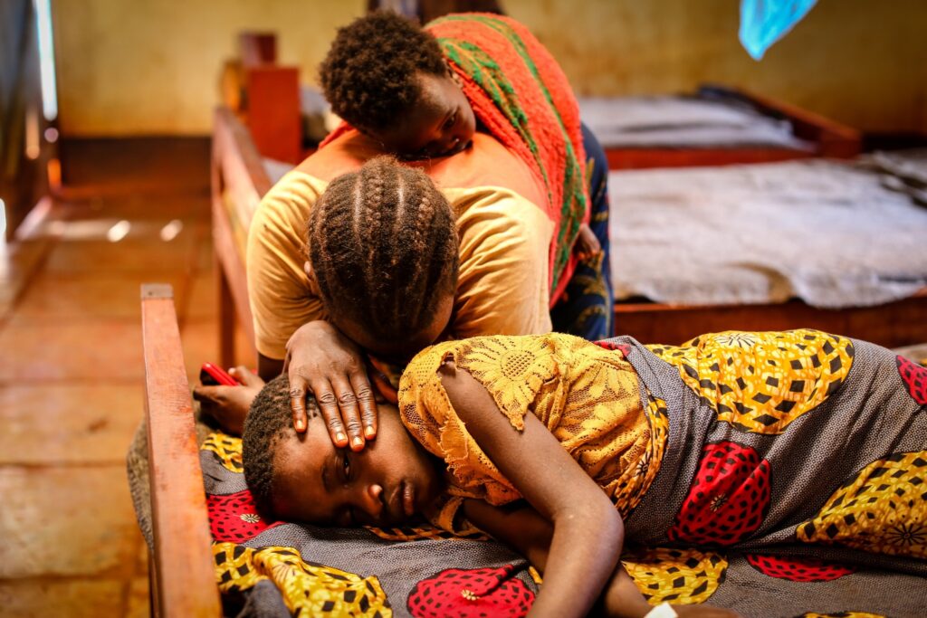 A weeping mother bends over her sick daughter (photo by Helen Manson)