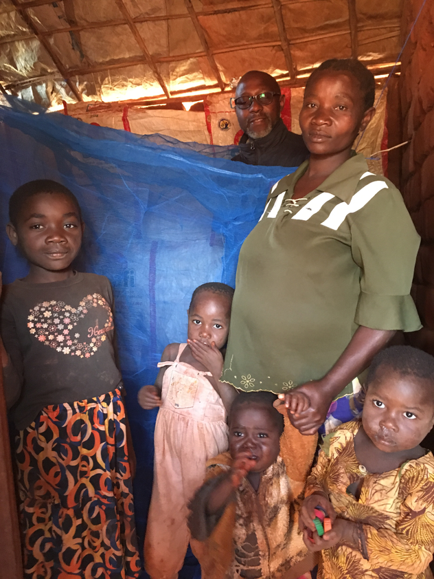A family of six stands next to a mosquito net