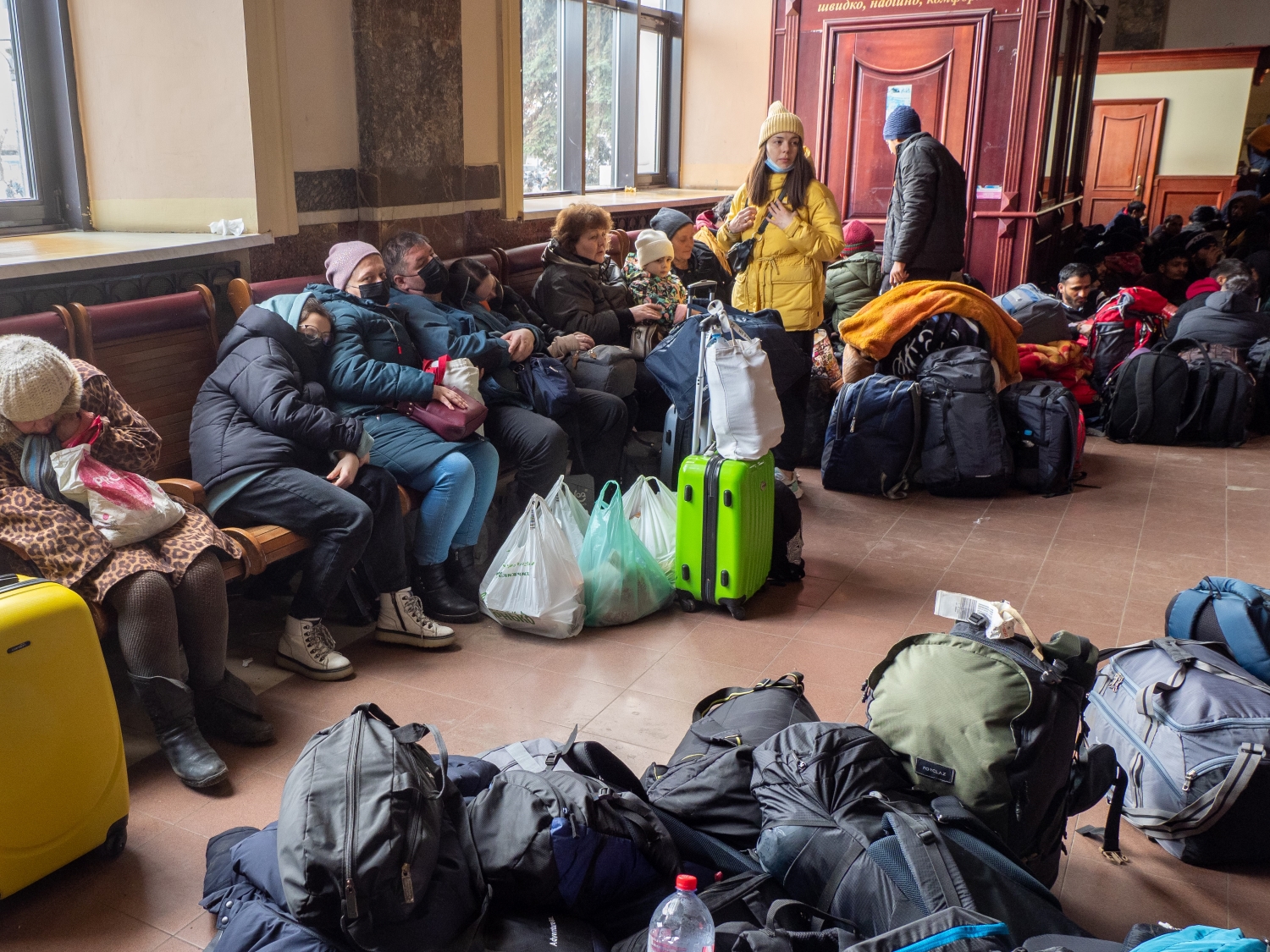 Ukrainian refugees huddle together with luggage while in transit. 