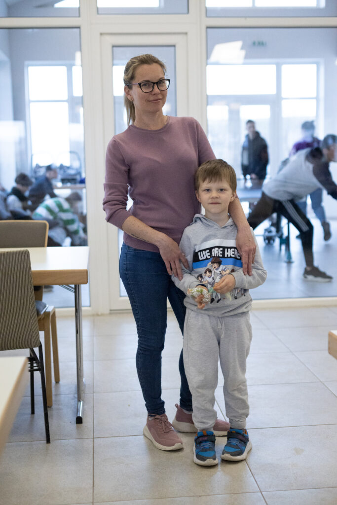 Maryna stands with her younger son Egor in the refugee accommodation center