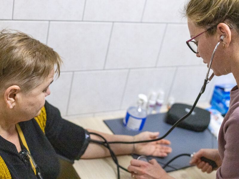 Maryna takes the blood pressure of a Ukrainian refugee at the accommodation center