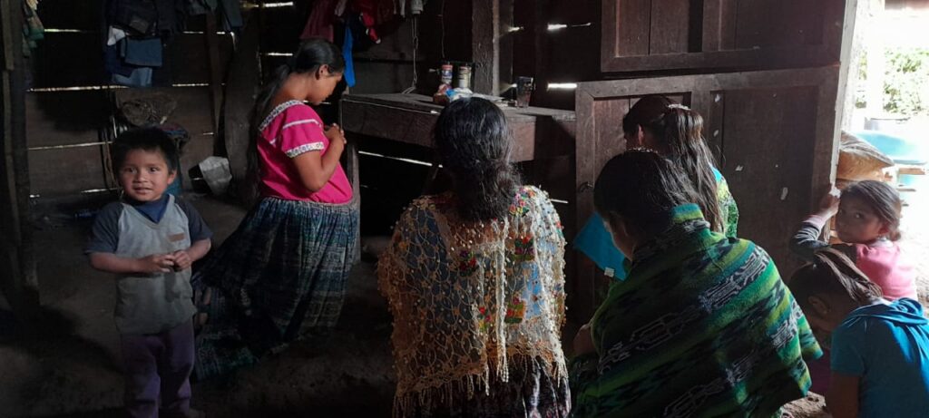 A group of women and children stand inside a home in Guatemala.