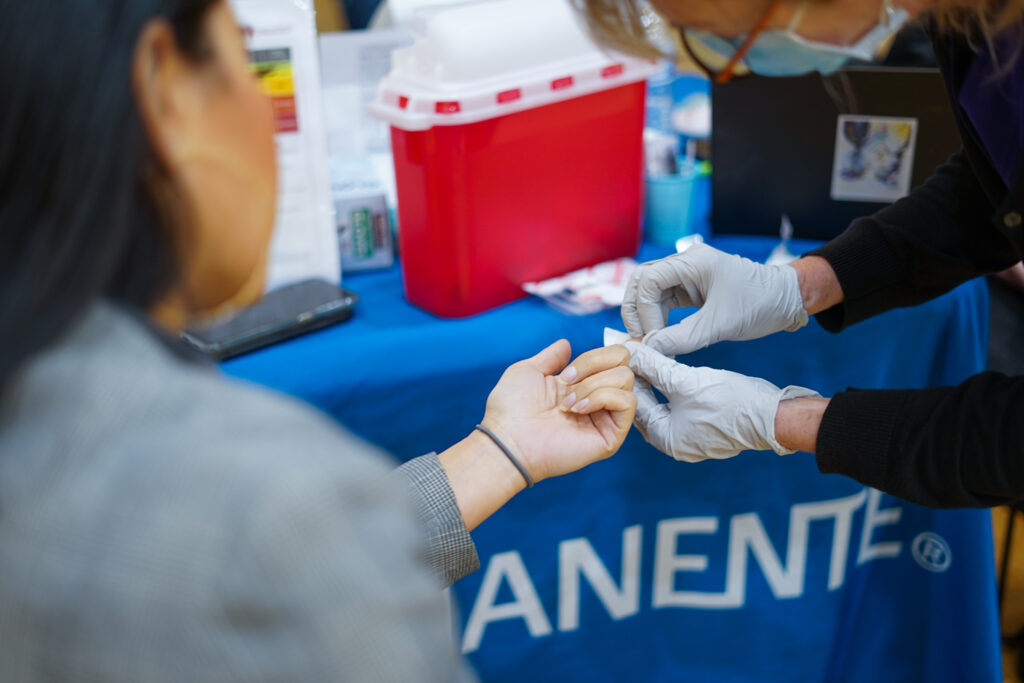 A woman gets a finger prick from a nurse to test for diabetes.