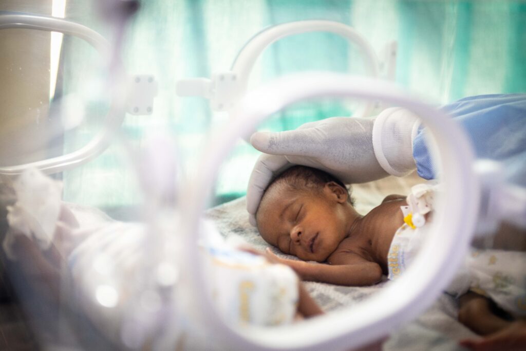 A premature baby sleeps inside an incubator. 